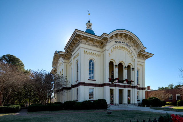 The Caswell courthouse, an ornate, cream-colored building in the middle of Yanceyville. The front of the building has Christmas decorations.