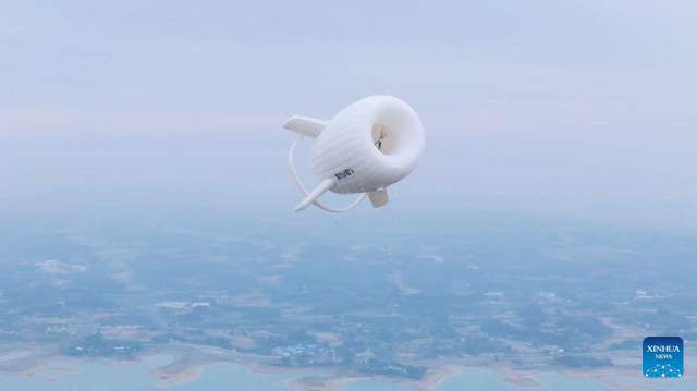 A inflatable structure, high in the sky, with a wind turbine inside, over the the Chinese countryside.