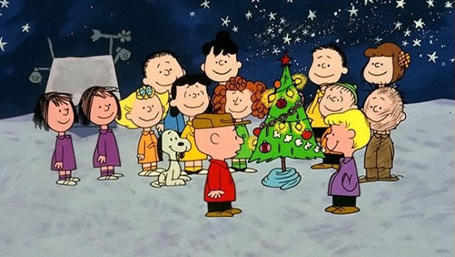 Snippet from the ending of the short with Charlie Brown and the rest of the children all standing in the snow, surrounding the now decorated small tree, and smiling.