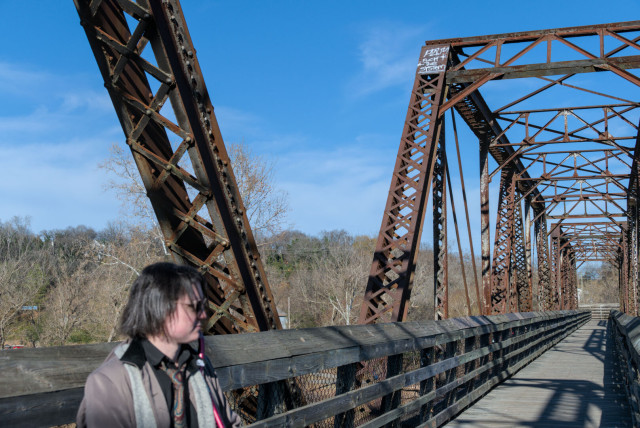 My fiancé standing on the bridge, with steel trusses behind them. Graffiti on one truss reads, "fuck the system."