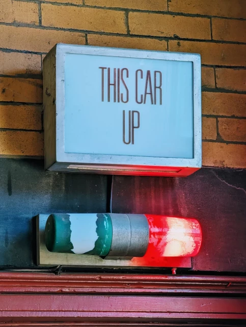 Old sign in cable car reading "This car up" and a red and green light below it