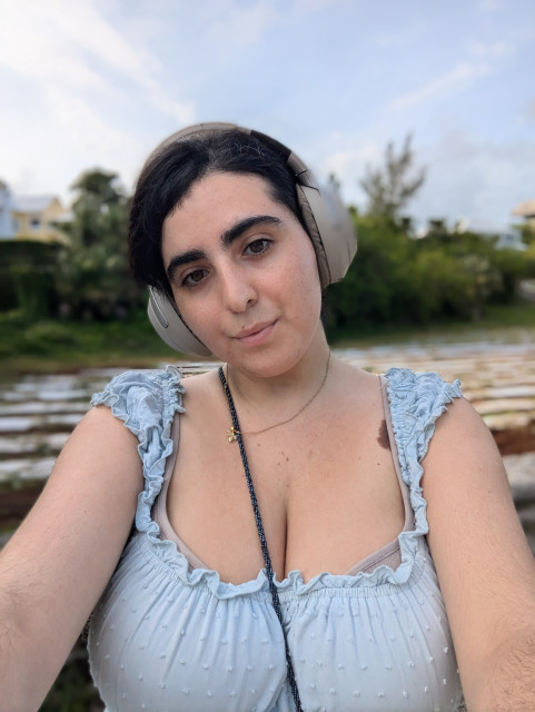 Selfie of me with my headset on and might blue showy dress with a field of crops in the background