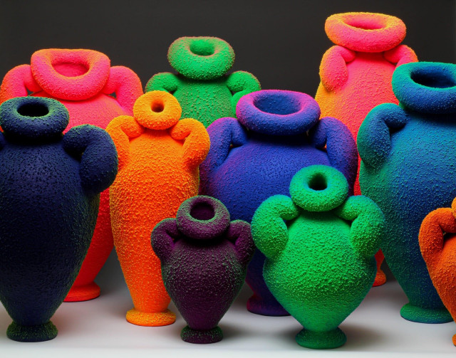 a group of seemingly glowing or fluorescing vase sculptures in different colors and pudgy shapes