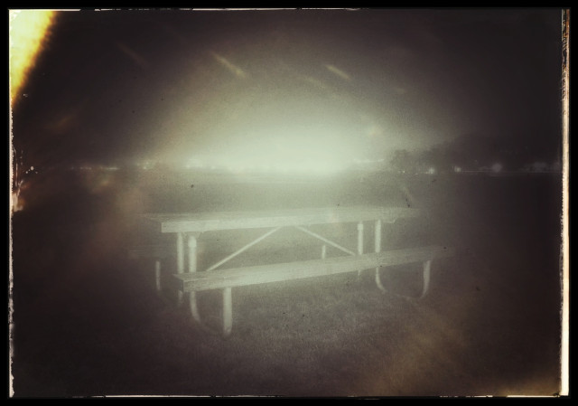 An unexciting picture of a picnic table on a foggy night in a park on the northern edge of San Francisco.

The picnic table was briefly lit by a flash from a flashlight, creating a pinhole effect. In the very far distance, on the horizon, there are city lights... overexposed and glaring.

Not shown: the photographer with a banged up knee.

Photography is dangerous.