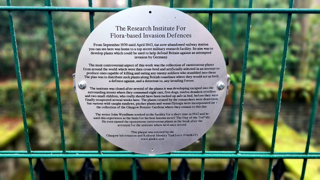 A plaque attached to a fence around an old railway station detailing an fanciful alternative history associated with it.