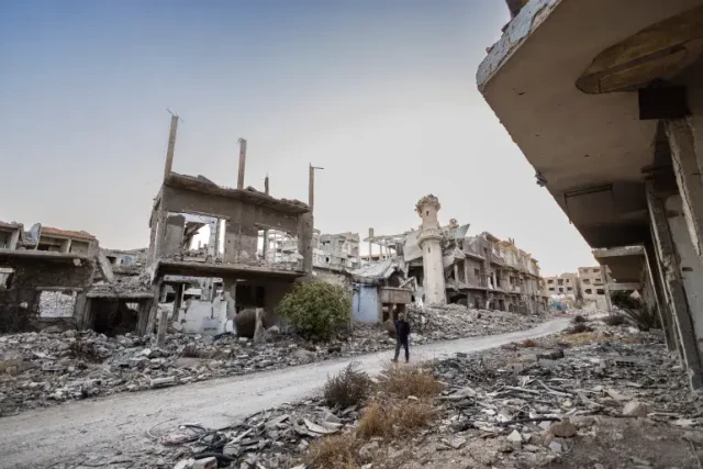 A Syrian man walks past destroyed buildings in the town of Jobar in Eastern Ghouta on the outskirts of Damascus on Saturday [Sameer Al-Doumy/AFP]