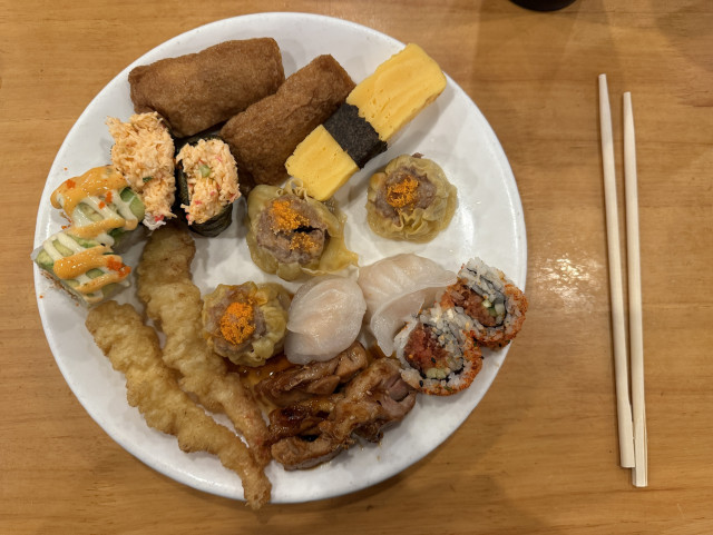 A plate of food including dim sum, sushi and tempura. 