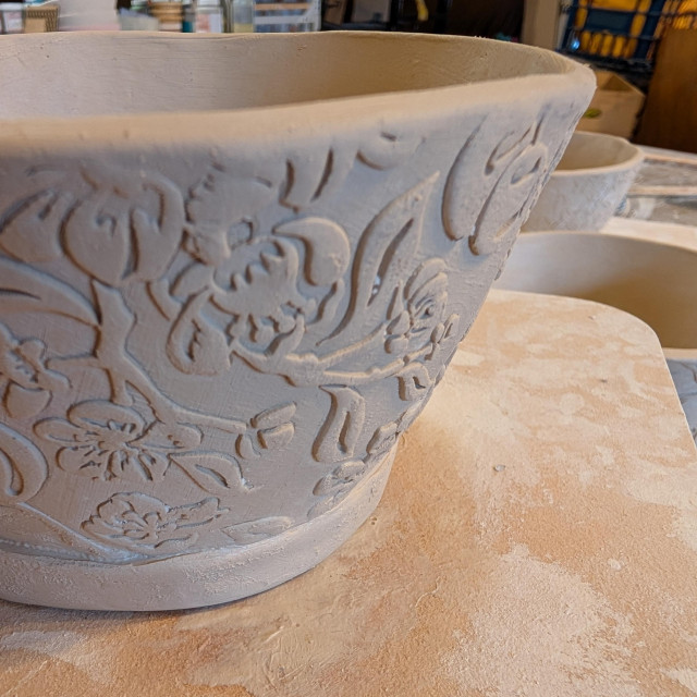 The hand-built bowl in the cherry/cherry blossom texture, finished but still damp greenware.