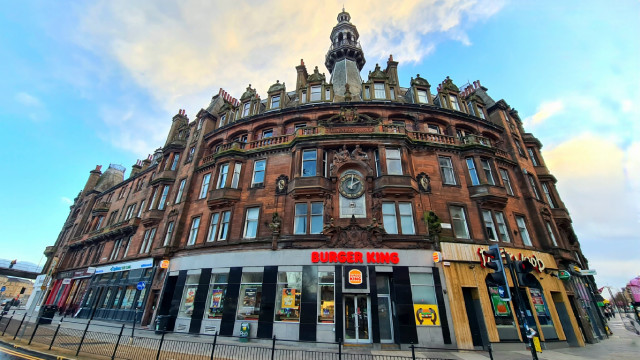 A large and ornate curving red sandstone tenement block.