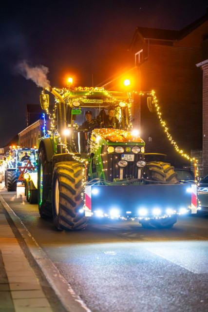 Ein geschmückter Traktor fährt durch eine enge Dorftstrasse. 