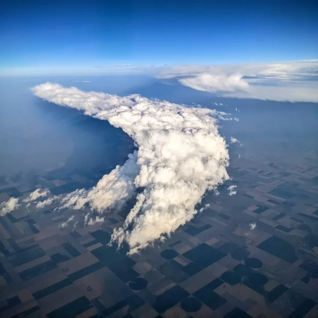 a crescent shaped cloud in the sky. Perspective is from an airplane window.