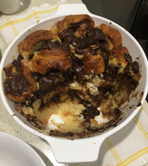 A Bread & Butter pudding, half consumed, showing the strata through its layers to the bottom of the cooking dish.