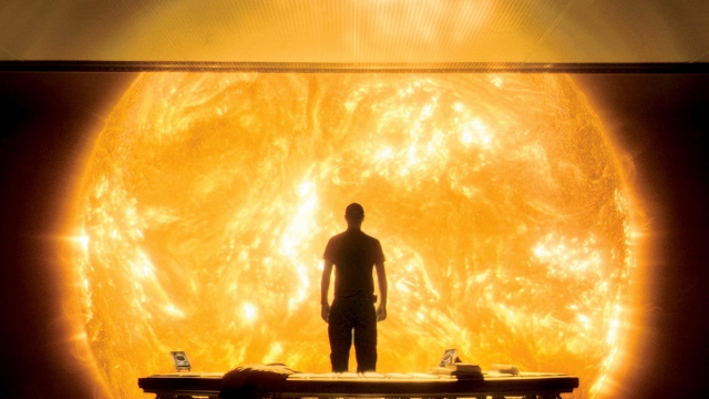 A man standing in an observation room. In front is the sun in all its glory.