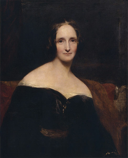 painting of Mary Shelley by Rothwell. It shows a white woman with sloping shoulders, dark hair and gold glasses
