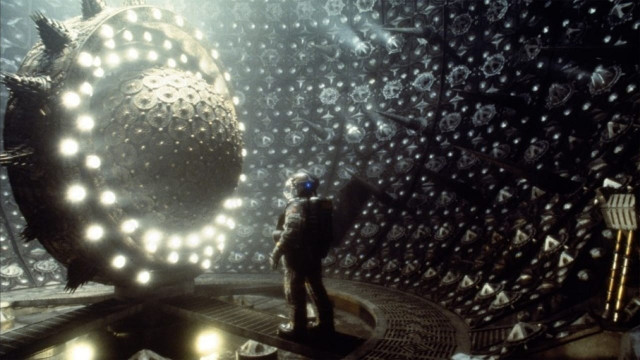 A space man standing in front of a glowing ball of balls. 