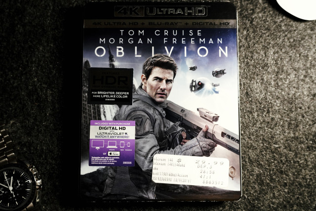 The Oblivion 4K UHD Blu-ray. An Apple Magic Mouse and Omega Speedmaster Professional are off in the corners.  