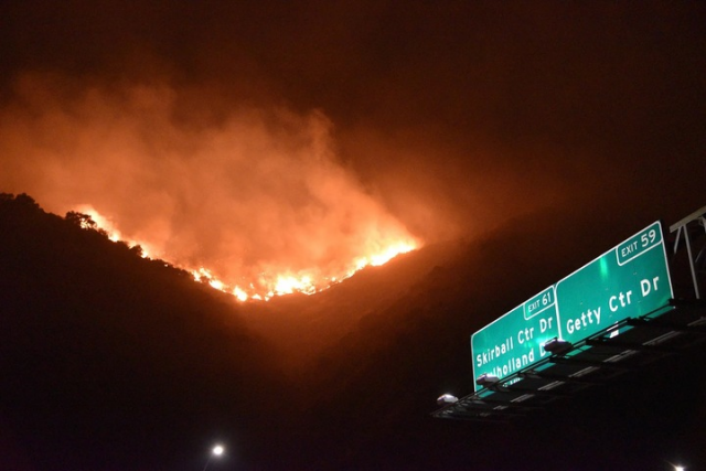 Fire crossing between two mountains, lit up against the night sky. There are a pair of green highway signs for Skirball Ctr Dr and Getty Ctr Dr visible in the corner.

Not sure if this is courtesy or Lauren Albrecht or if she got it from the news or a local friend, but she's the one who shared it with me.