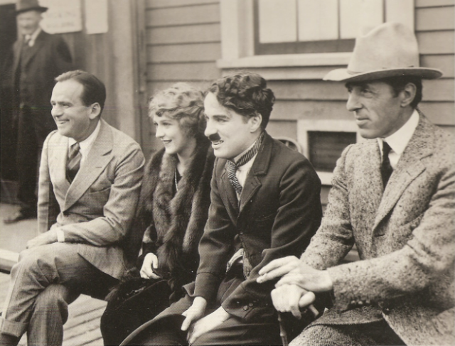 Douglas Fairbanks, Mary Pickford, Charlie Chaplin and D W Griffith sitting on a bench together to promote United Artists.