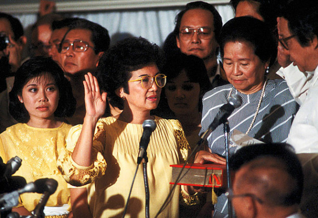 Corazon Aquino, dressed in yellow which was the colour of the revolution, being sworn in as President. She is a Filipino woman with dark hair.