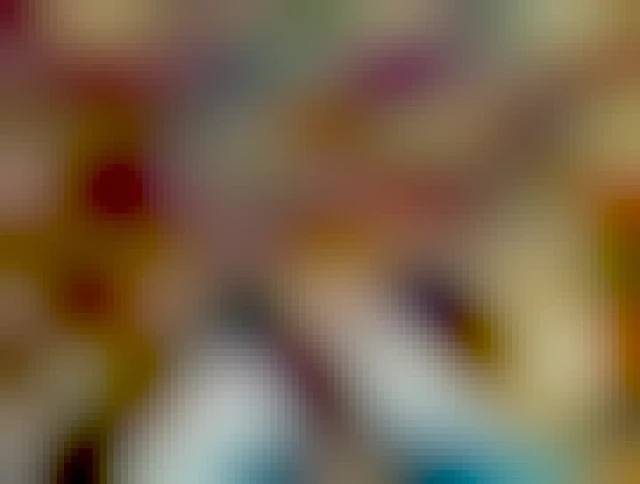 Looking down the photographers legs and shoes can be seen standing in a large pile of fallen leaves. Gold's, yellows, brown and green can be seen in the wide variety of leaves.