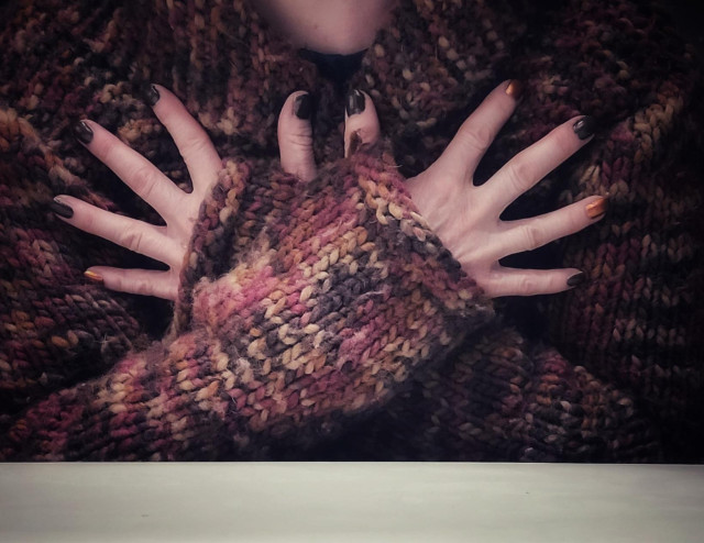 A person in a woollen, all autumn colours, cardigan, holding her arms crossed in front of her chest, fingers stretched. The nails are polished with two different colours. On one hand, the nail of the little finger has a golden colour, while all the others are painted in dark brown. The nails on the other hand, the index and ring fingers are painted in the golden colour, while the others are in dark brown. The different colours represent a code.If you want to guess, please put your answer behind a cw...just not to potentially spoil for others 😊