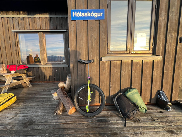 A unicycle and backpacks in front of a cabin
