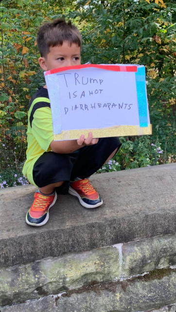 Child holding a hand made sign that says, "Trump is a Hot Diarheapants" 