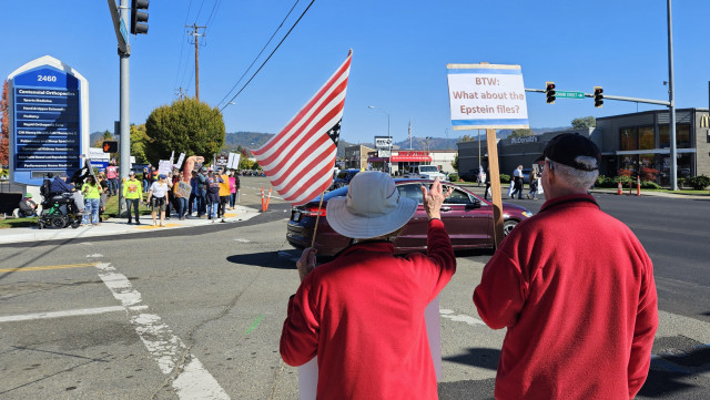 elders crossing the street during a protest carrying a sign about the Epstein files