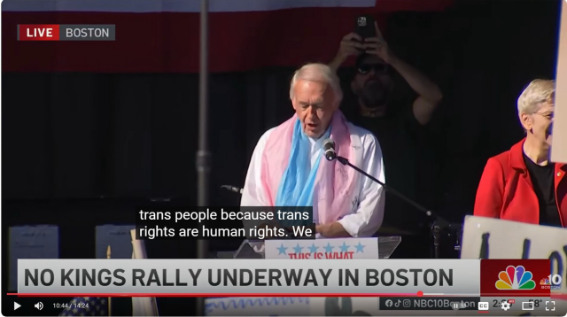 Photo of Ed Markey at the no kings Boston event wearing a trans flag as a scarf 