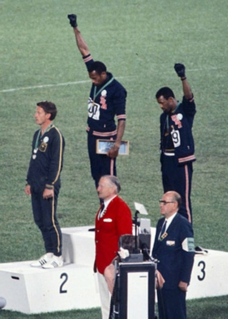 Gold medalist Tommie Smith (center) and bronze medalist John Carlos (right) showing the raised fist on the podium after the 200 m race at the 1968 Summer Olympics; both wear Olympic Project for Human Rights badges. Peter Norman (silver medalist, left) from Australia also wears an OPHR badge in solidarity with Smith and Carlos. By Angelo Cozzi (Mondadori Publishers) - This file has been extracted from another file, Public Domain, https://commons.wikimedia.org/w/index.php?curid=40937149