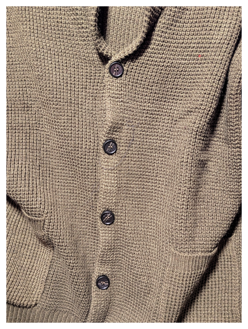 close-up of a gray/sage knit cardigan with shawl collar, pockets and black buttons.