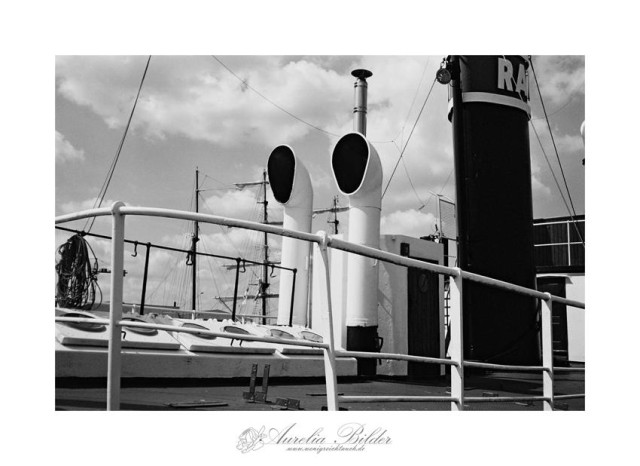 Bild ist in sw, es zeigt die Reling und Schornsteine eines alten Stahlschiffs aus den 1930ern. 