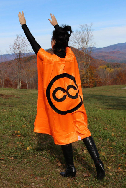 A person shown from behind wearing an orange cape with the CC Creative Commons logo on it.