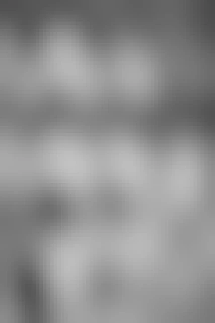 Snow-covered rocks on the shore of a frozen Taggart Lake. In the background, Grand Teton, Mount Owen, and Teewinot Mountain.