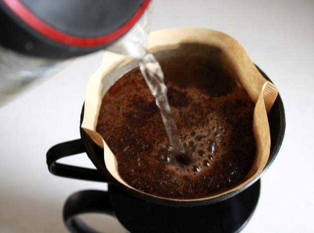 Making coffee. Shows pouring water over coffee grounds in a filter.