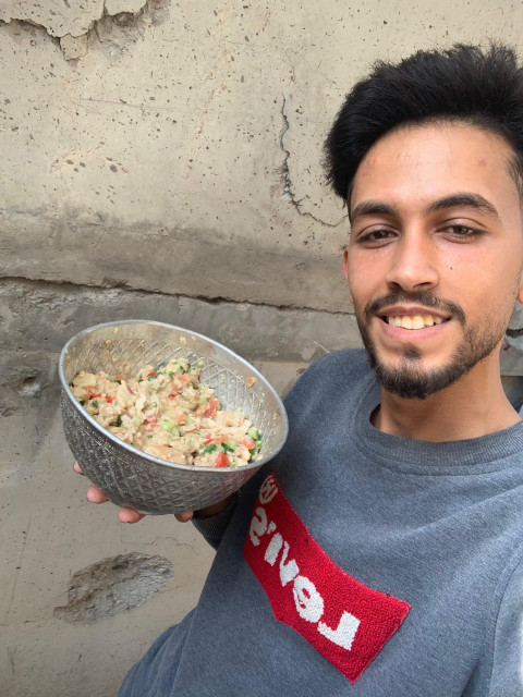 Mohammed Shobair, 23 years old, from Gaza, holding a bowl of Fattoush.