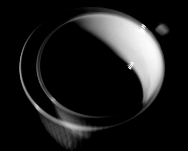 An almost square image of a coffee cup seen a bit from above. The image is made with zoom during exposure that makes it look like a cup with a smaller one inside. This for making some kind of motion.