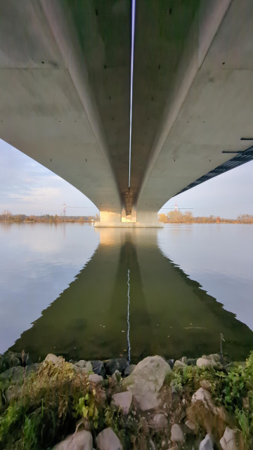 Betonbrücke von unten. Man sieht den Trennspalt beider Brückenteile vertikal auch sich im Wasser spiegelnd