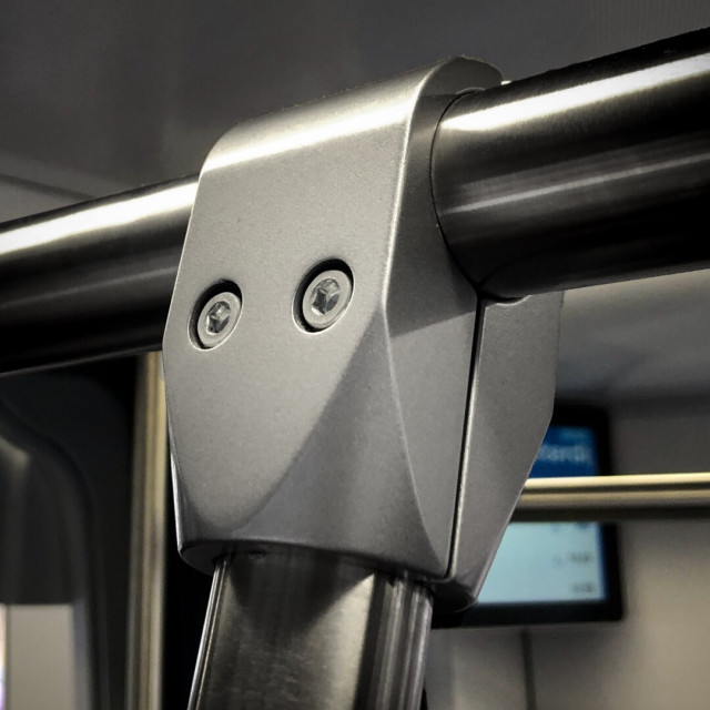 Close-up of a detail of metal support rail in Amsterdam public transport car with a chunky section with two screws that resemble eyes, in the middle of the frame.