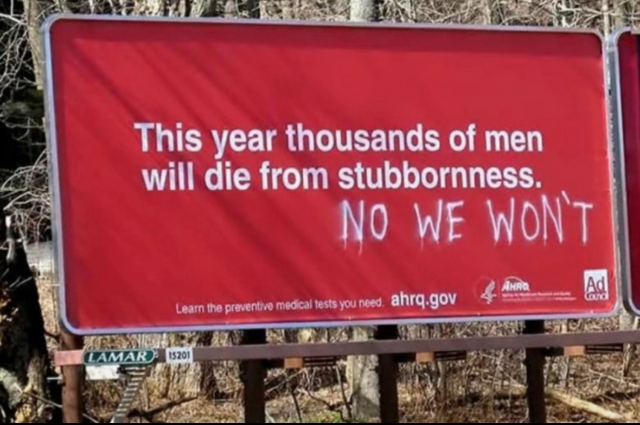 Billboard about preventive medical care: This year thousands of men will die from stubbornness. Below this message someone has spray painted: NO WE WON’T