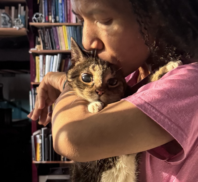 Pico with eyes wide in the sunlight, realizing she can’t avoid the kiss