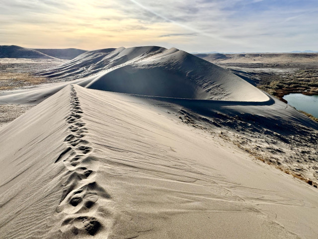 Similar type of pic as in upper right pic, but view from opposite end of sand dunes looking back into the sun. From this view the lake at the base is at the right side. The multiple peaks of the ridgeline can be seen from this view. 