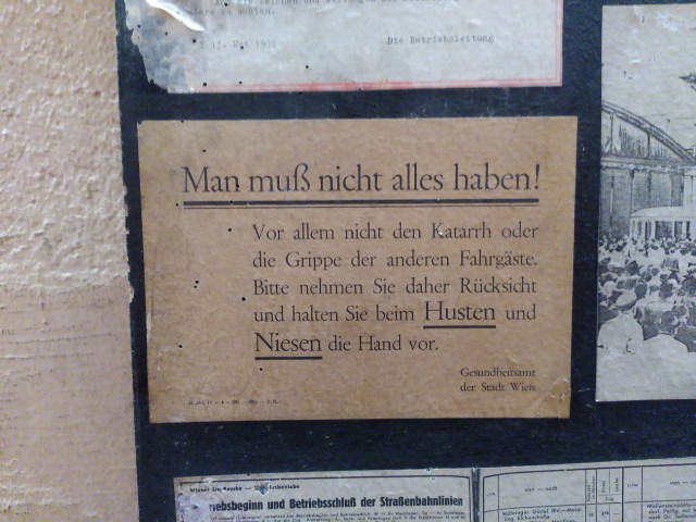 Altes Plakat mit Text: "Man muß nicht alles haben! Vor allem nicht den Katarrh oder die Grippe der anderen Fahrgäste. Bitte nehmen Sie daher Rücksicht und halten Sie beim Husten oder Niesen die Hand vor. Gesundheitsamt der Stadt Wien."