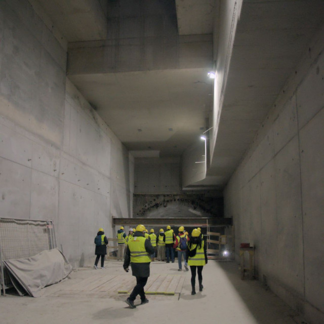 people in high-vis vests in an underground construction site with planar concrete walls