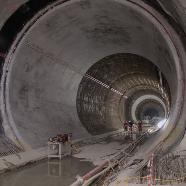 view into a circular tunnel. closer to the viewer the walls are finished with poured concrete further into the tube the rebar is still out