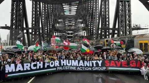 Huge crowd march behind a banner reading MARCH FOR HUMANITY SAVE GAZA