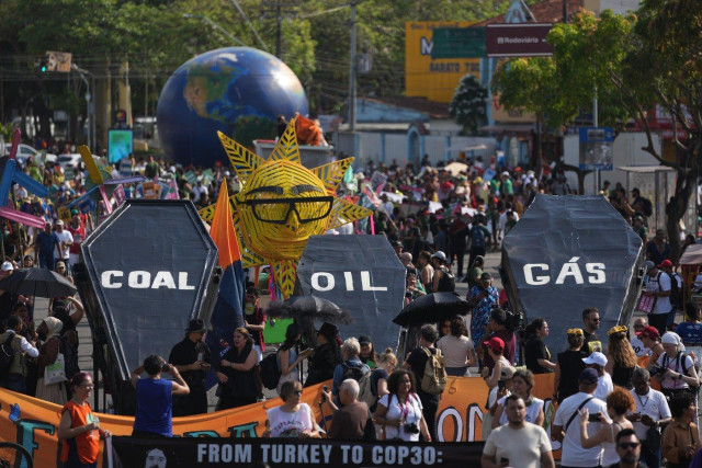 Huge crowds carry giant black coffins marked COAL, OIL and GAS through the streets of Belem.