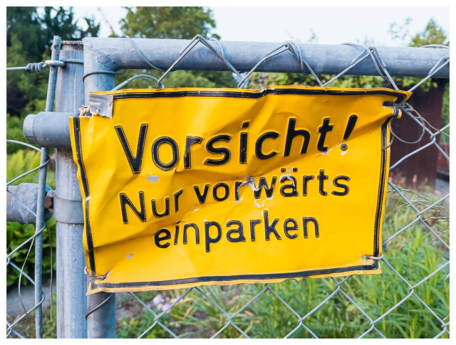 Stark verbeultes Schild "Vorsicht - Nur vorwärts einparken" - offensichtlich hat hier wer rückwärts eingeparkt.