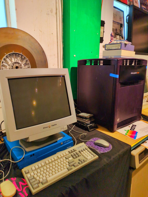 A very blue Silicon Graphics computer under a beige monitor, that's next to a massive purple cube workstation.