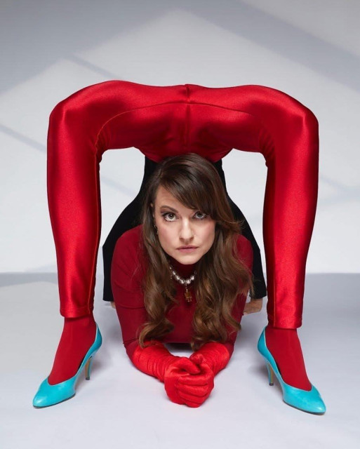 une contorsionniste en rouge allongée entre ses pieds
